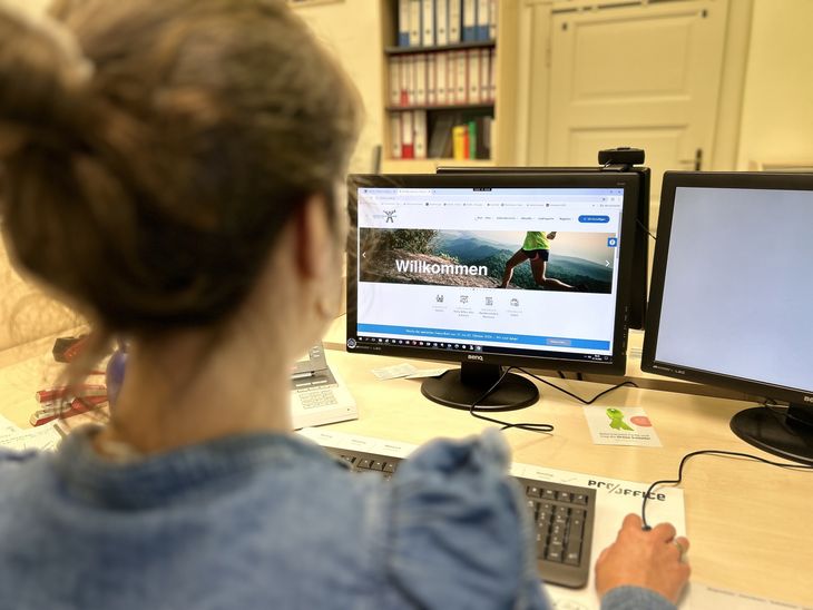 Eine Frau sitzt vorm Rechner und surft auf der Seite www.resilienz-pfalz.de